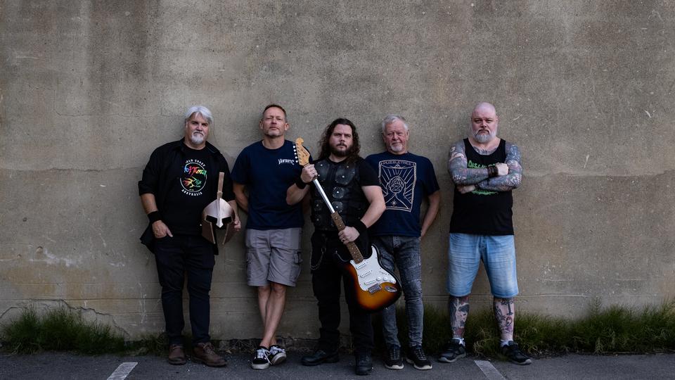 The five members of Kromiius standing together against a concrete wall
